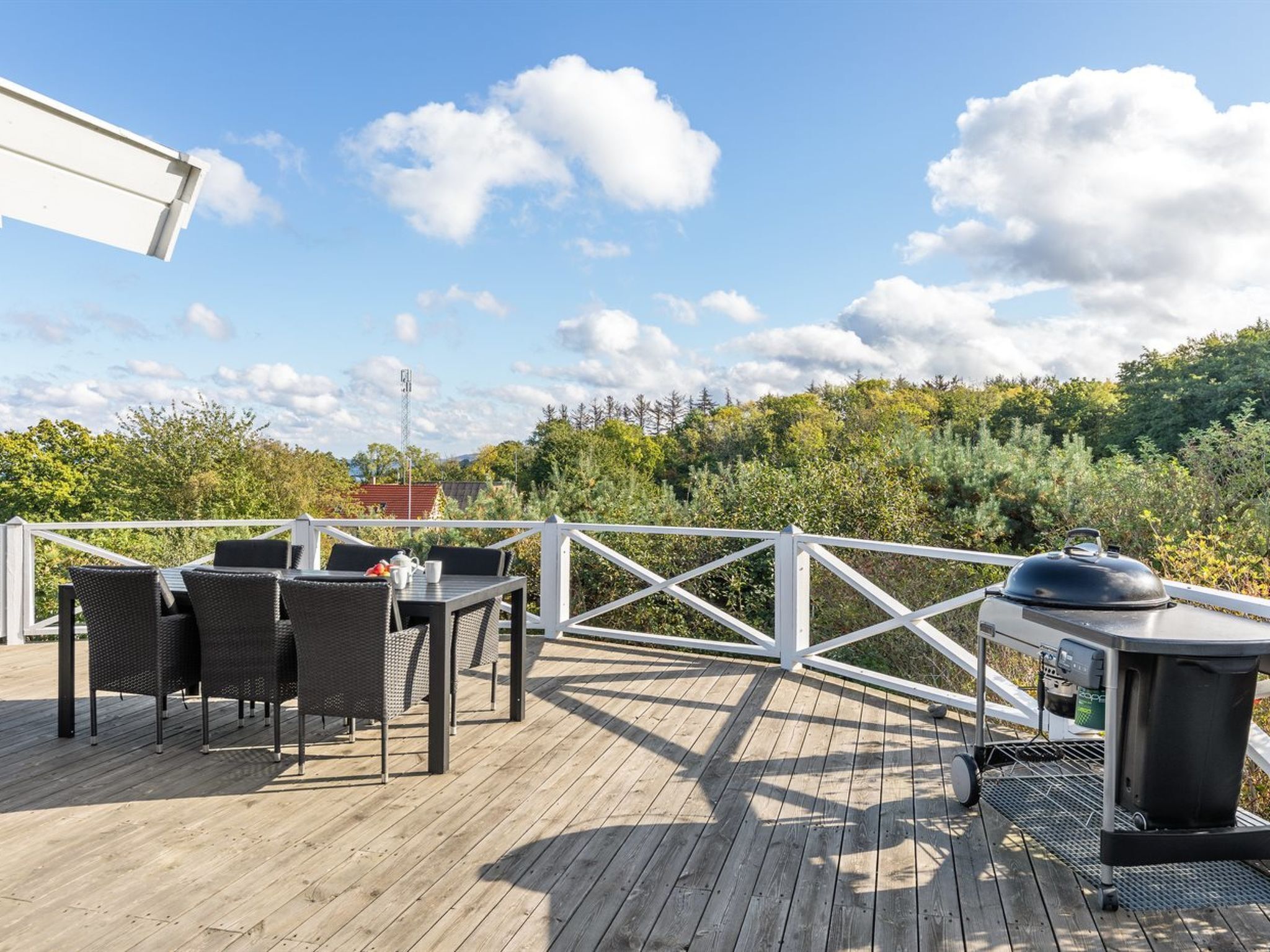 A wooden deck with outdoor furniture and a barbecue grill.