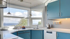 A modern kitchen with blue cabinets, a white countertop, a sink, and pendant lights. - "Tjelle" - 300m from the sea by Interhome (Allinge)