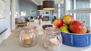 A modern kitchen with a dining area, featuring a blue bowl of apples and two glass candle holders on the counter. - "Tjelle" - 300m from the sea by Interhome (Allinge)
