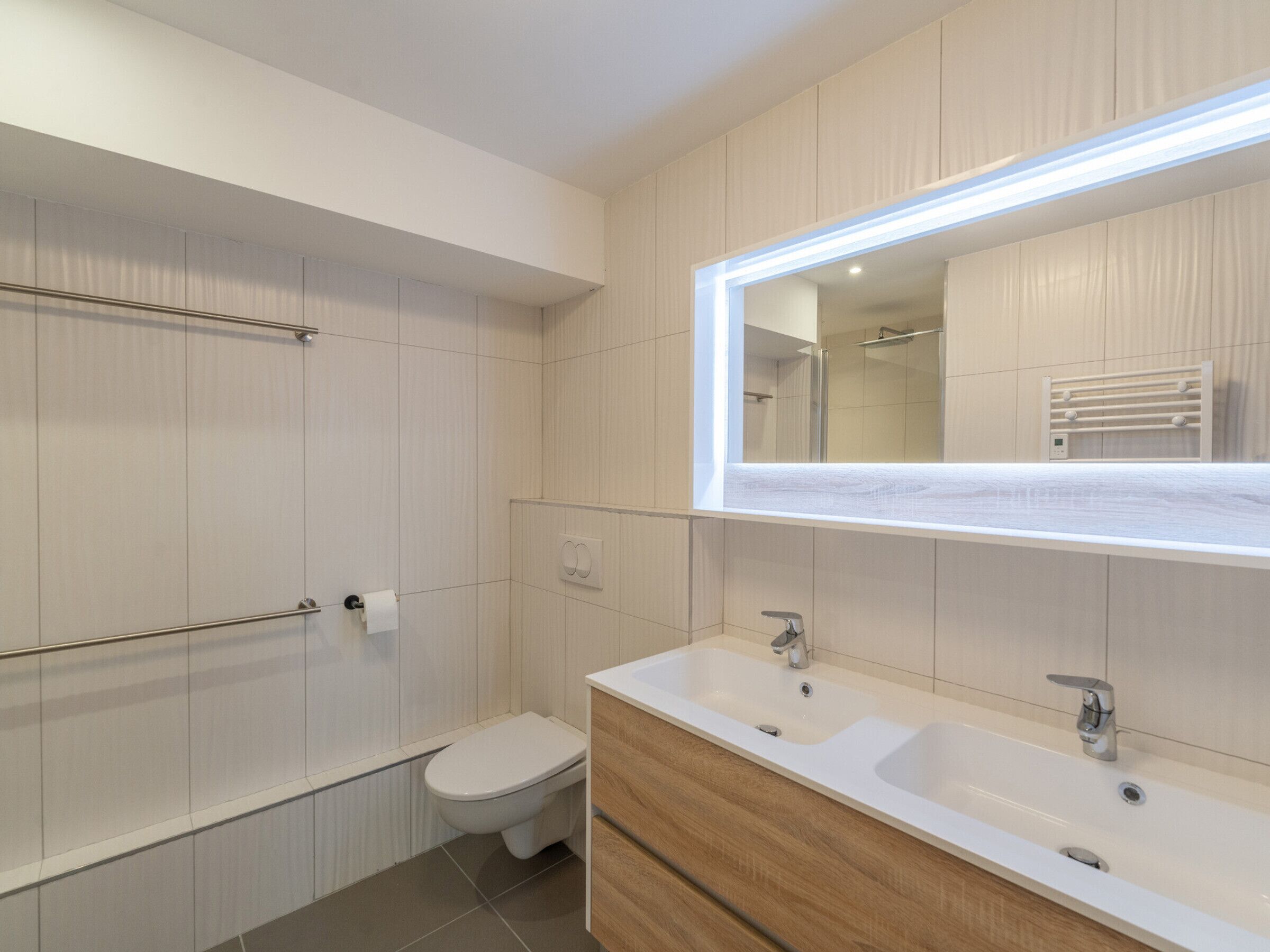 A modern bathroom with a toilet, a sink, and a shower.