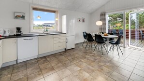 Eine moderne Küche mit Essbereich, großen Fenstern und Blick ins Freie.