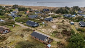 Ein Luftbild einer Küstenwohngegend mit mehreren Häusern, einem Sandstrand und einem Gewässer im Hintergrund.