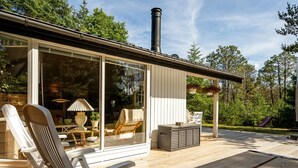 A wooden deck with outdoor furniture, a glass door entrance, and a chimney.