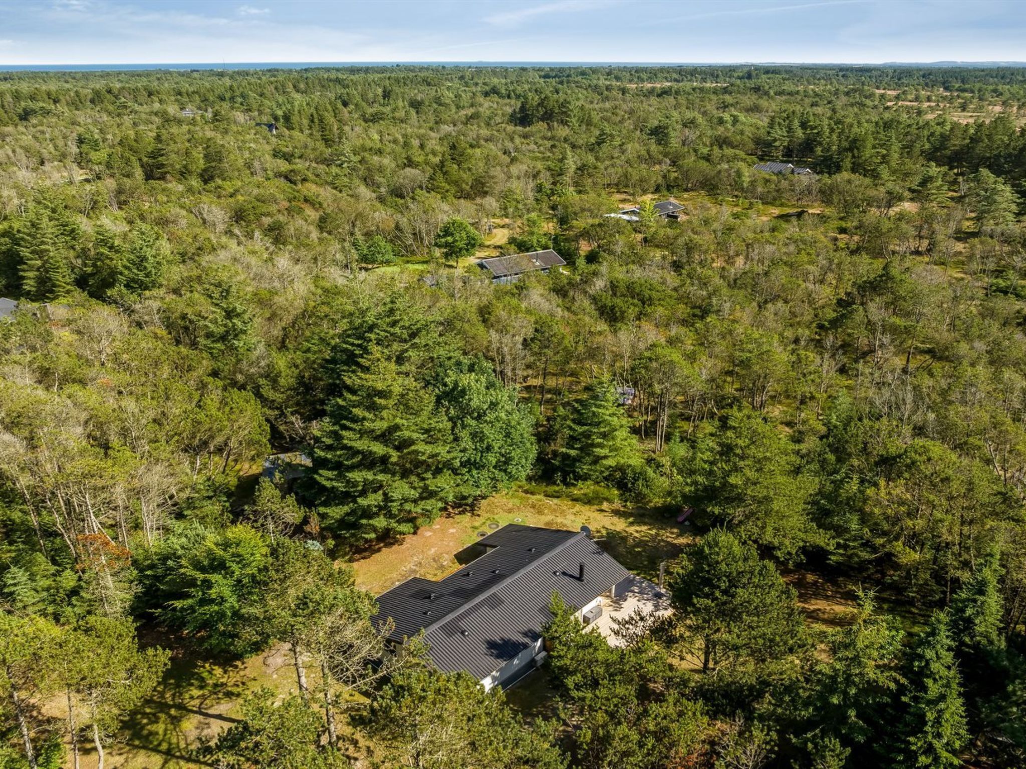 A house surrounded by dense forest, with a clear view of the surrounding trees and landscape.