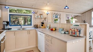A modern kitchen with wooden cabinets, a built-in dishwasher, and a large window.