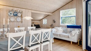 A cozy cabin interior with a dining area, a sofa, and a window with blinds.