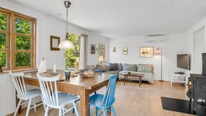 A cozy living room with a wooden dining table, blue and white chairs, a sofa, and a fireplace. - "Carly" - 100m from the sea by Interhome (Væggerløse)