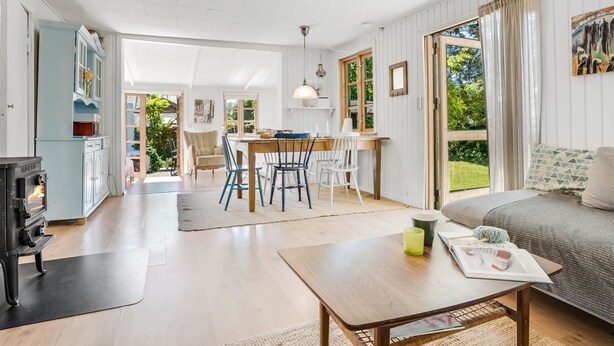 A spacious living area with a wooden dining table, a sofa, and a fireplace. - "Carly" - 100m from the sea by Interhome (Væggerløse)