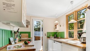 A modern kitchen with green paneling, a wooden countertop, and a view of the outdoors through large windows. - "Carly" - 100m from the sea by Interhome (Væggerløse)