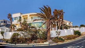 A modern multi-story building with a curved facade, surrounded by palm trees and a landscaped garden. - Sir David Baird 22 (Cape Town)