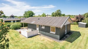 Een gelijkvloers huis met een omheinde achtertuin, een klein terras en een tuinhuis.