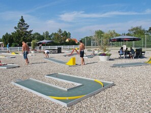 Un espace de loisirs en plein air doté d’une surface en gravier, d’équipements d’exercice et de zones aménagées pour s’asseoir.
