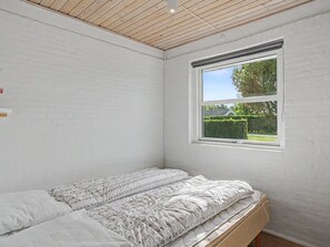 A room with a bed, a window, and a white brick wall.