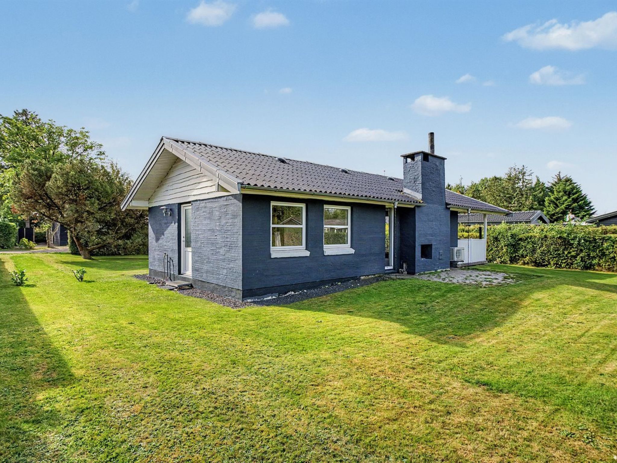 A single-story house with a gabled roof, a chimney, and a well-maintained lawn.