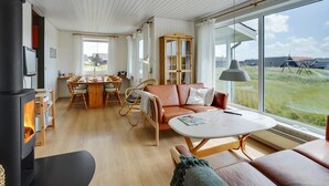 Un salon spacieux doté d’une grande fenêtre, d’une cheminée, d’un coin repas et d’un espace salon confortable.