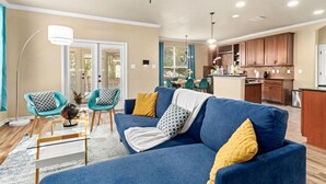 Una sala de estar moderna con un sofá azul, sillas color verde azulado y una mesa de centro de vidrio.