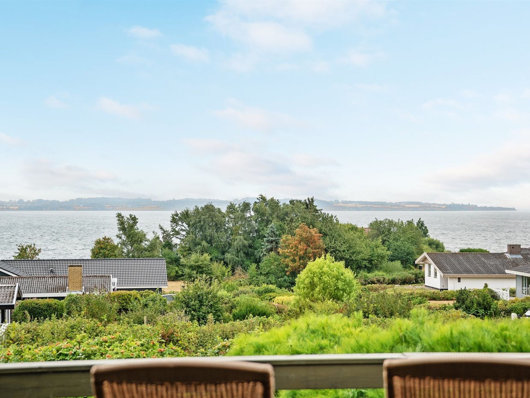 A residential area with houses, a view of the water, and a chair in the foreground.