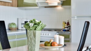 Una cocina moderna con una mesa de comedor, un jarrón de flores y un plato de fruta.