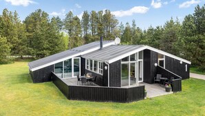 A modern, black wooden cabin with a sloped roof, large glass windows, and a deck area with outdoor seating. - "Halwarth" - 250m from the sea by Interhome (Jerup)