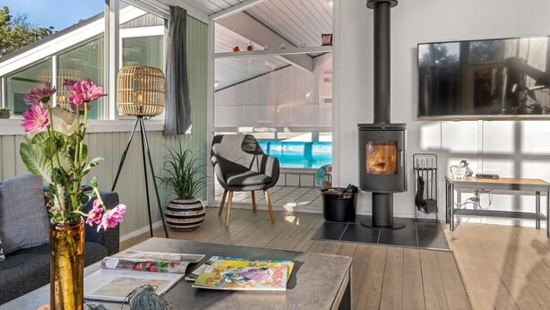 A modern living room with a large window, a fireplace, a comfortable sofa, a coffee table with magazines, and a potted plant. - "Halwarth" - 250m from the sea by Interhome (Jerup)