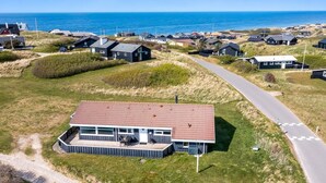 Vista aérea de una zona residencial costera con casas, un camino pavimentado y una playa al fondo.