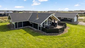 Une rangée de maisons modernes, de plain-pied, avec des toits inclinés, un patio couvert et une pelouse verdoyante.