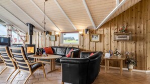 Un intérieur de chalet chaleureux avec une cheminée, un canapé en cuir, des murs en bois et un coin repas.