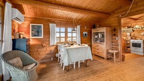 Ein gemütliches Blockhauskamin mit Esstisch, Korbsessel, Holzschränken und einer Küchenzeile.