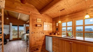 Ein Holzblock-Interieur mit Küche, Essbereich und Blick durch die Fenster.