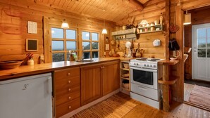 Eine Holzhütte mit einer Küche, inklusive Kühlschrank, Herd, Spüle und Holzschränken.