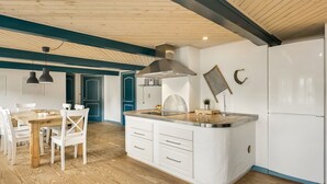 Une cuisine moderne dotée d’un îlot central, de meubles blancs et d’un plafond en bois.