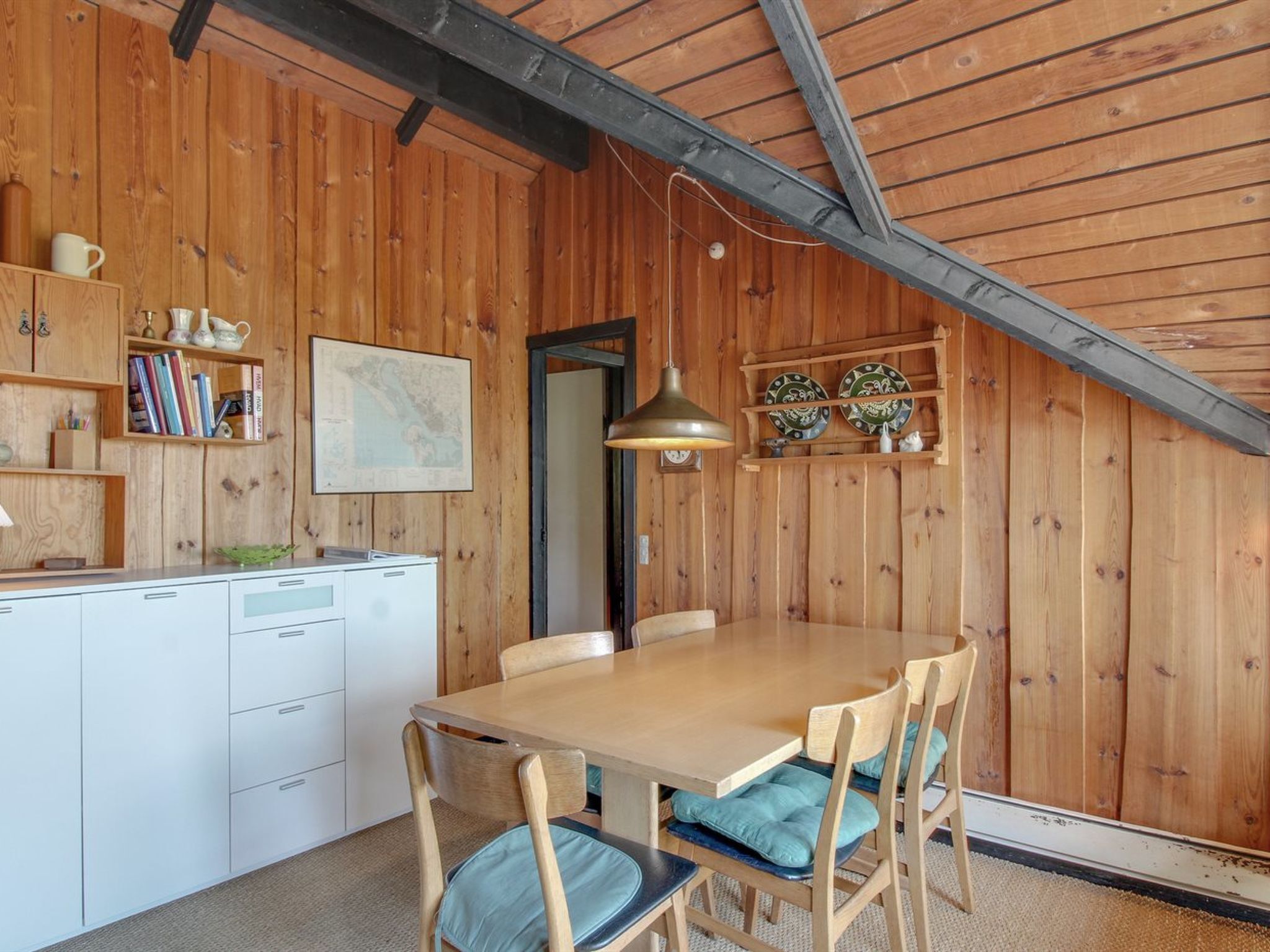 Una cocina acogedora con paredes de madera, una mesa de comedor, sillas y una lámpara colgante.