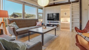 Ett modernt vardagsrum med ett stort fönster, en soffa, ett soffbord och en tv.