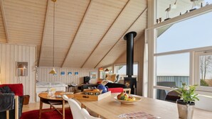 A cozy cabin interior with a wooden ceiling, a dining area with a red rug, and a large window offering a view of the outdoors. - "Hane" - 150m from the sea by Interhome (Hadsund)