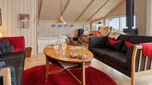 A cozy cabin interior with a wooden ceiling, a sofa, a red rug, and a table with a bottle and glasses. - "Hane" - 150m from the sea by Interhome (Hadsund)