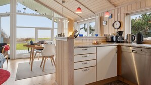 A modern kitchen with wooden cabinets, a stainless steel dishwasher, and a large window offering a view of the outdoors. - "Hane" - 150m from the sea by Interhome (Hadsund)