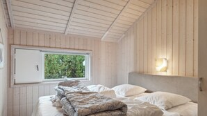 A bedroom with a bed, a window, and a wall-mounted light fixture. - "Hane" - 150m from the sea by Interhome (Hadsund)