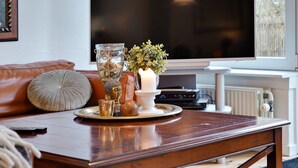 Ein Wohnzimmer mit Couchtisch aus Holz, Fernseher und Kamin.