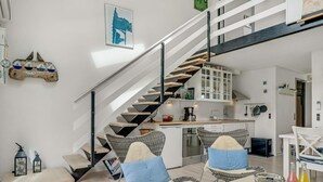 Un interno moderno con una scala, sedie in vimini, un tavolo da pranzo e un angolo cottura.