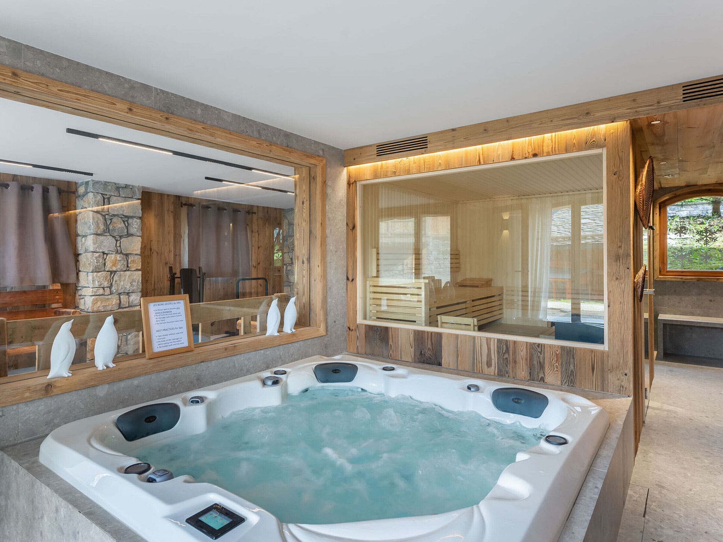 Een moderne badkamer met een grote spiegel, een houten wastafelmeubel en een whirlpool.