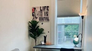 A bedroom with a bed, a desk, a radiator, a window with blinds, a lamp, and a poster on the wall. - Pet-Friendly Space, King bed, Office (Halifax)