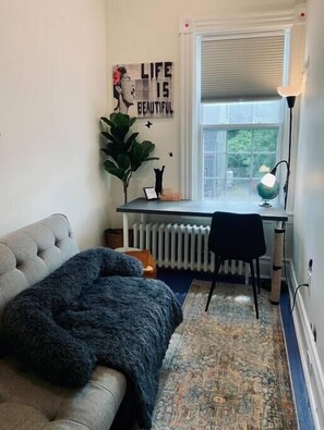 A cozy room with a sofa, a desk, a radiator, a lamp, and a poster on the wall. - Pet-Friendly Space, King bed, Office (Halifax)