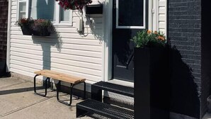 A white building with a black mailbox, a bench, and hanging flower baskets. - Pet-Friendly Space, King bed, Office (Halifax)