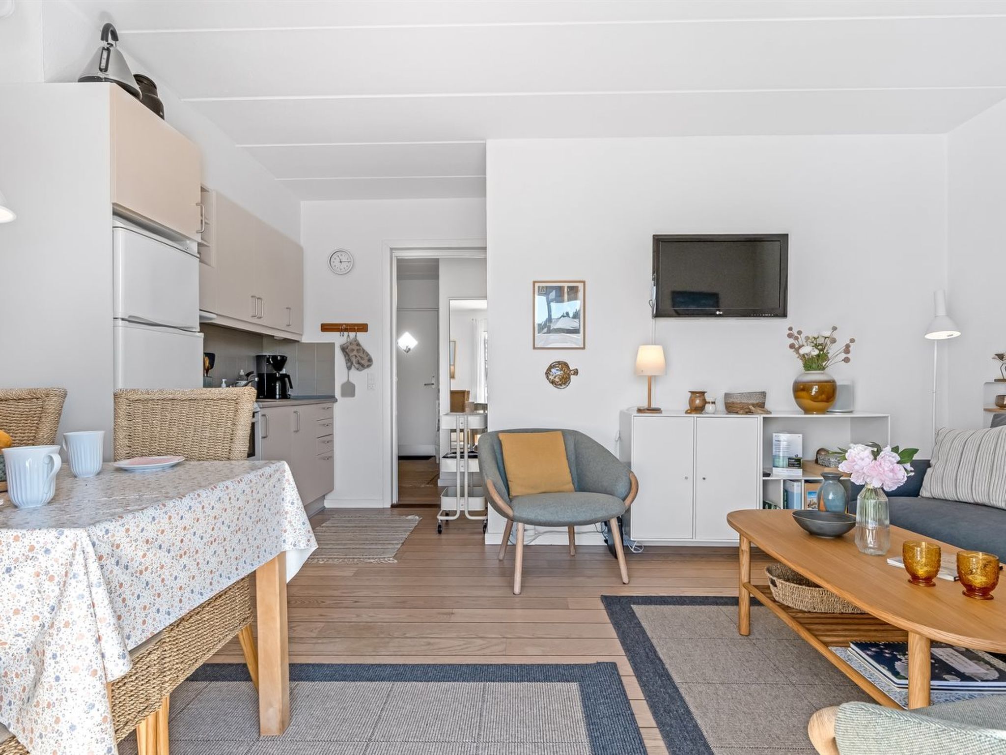 En kompakt opholdsstue med tekøkken, spiseplads og siddeområde.