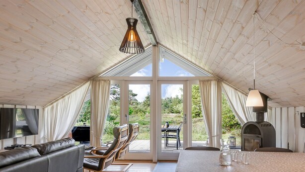 Een gezellige, open woonruimte met een loft-plafond, een bank, een eettafel en een grill.