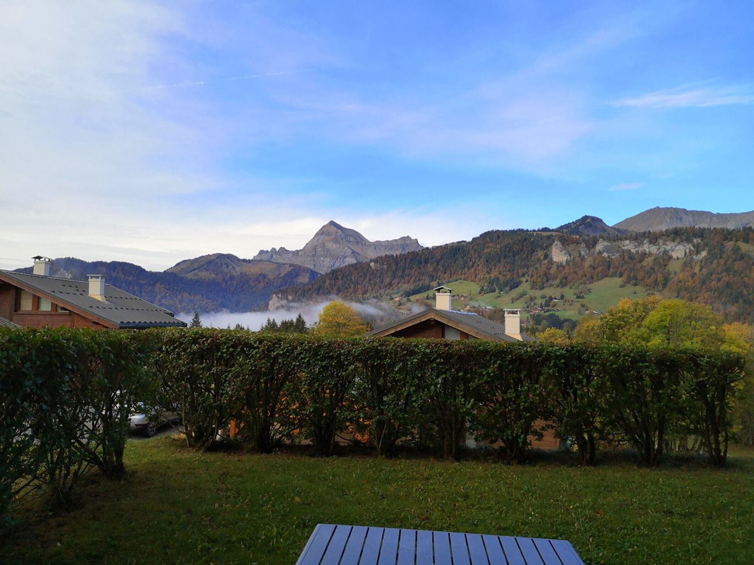 Eine Berglandschaft mit einem Haus und einem Garten im Vordergrund.