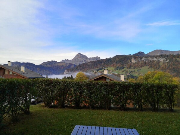 A mountainous landscape with a house and a garden in the foreground.