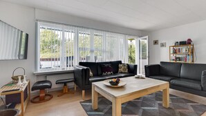 Een moderne woonkamer met een zwarte bank, een houten salontafel en een boekenkast.