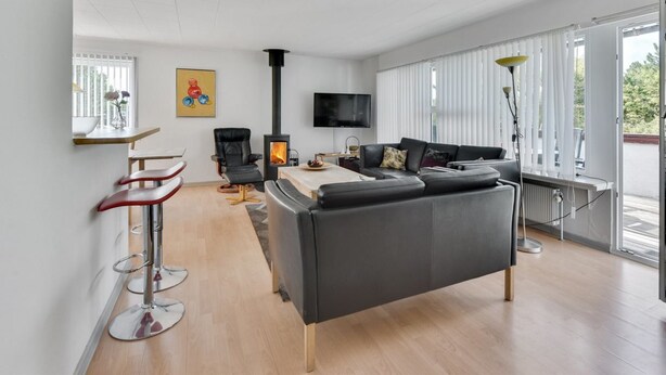 Een moderne woonkamer met een zwarte bank, een houten salontafel, een televisie en een open haard.