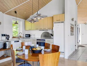 A modern kitchen with wooden cabinets, a built-in oven, and a dining area with a round table and chairs. - "Adrienne" - 35km from the sea by Interhome (Toftlund)